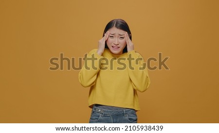 Unhappy adult rubbing temples to cure headache problem, suffering from tension and migaine in studio. Unwell person feeling displeased and overwhelmed because of pain. Woman in despair