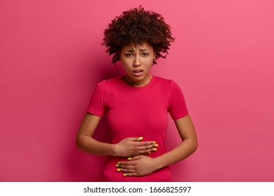 Unhappy African American Female Feels Unwell, Has Stomach Ache Because Of Food Poisoning, Abdominal Main, Menstruation Period Cramp, Nausea, Painful Diseases And Diarrhea, Grimaces From Pain