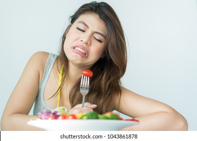 Unhappy Asian Women Is On Dieting Time Looking At Tomato On The Fork. Girl Do Not Want To Eat Vegetables And Dislike Taste Of Tomato.