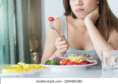 Unhappy Asian Women Is On Dieting Time Looking At Tomato On The Fork. Girl Do Not Want To Eat Vegetables And Dislike Taste Of Vegetable.