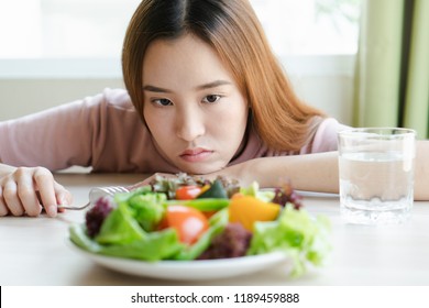 Unhappy Asian Women Is On Dieting Time Looking At Broccoli On The Fork. Girl Do Not Want To Eat Vegetables And Dislike Taste Of Vegetable.