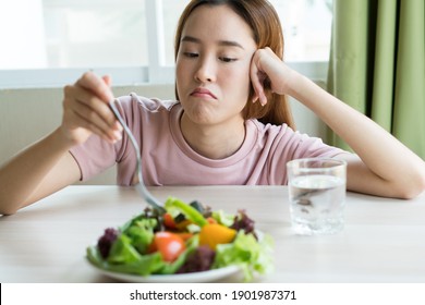 unglückliche asiatische Frauen sind auf Diät Zeit schauen Broccoli auf der Gabel. Mädchen wollen kein Gemüse essen und den Geschmack von Gemüse nicht mögen.