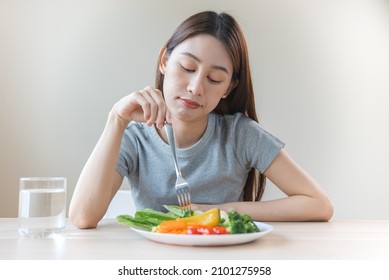 Unhappy Asian Women Is On Dieting Time Looking At Broccoli On The Fork. Girl Do Not Want To Eat Vegetables And Dislike Taste