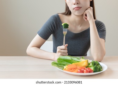 Unhappy Asian Women Is On Dieting Time Looking At Broccoli On The Fork. Girl Do Not Want To Eat Vegetables And Dislike Taste