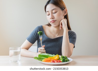 Unhappy Asian Women Is On Dieting Time Looking At Broccoli On The Fork. Girl Do Not Want To Eat Vegetables And Dislike Taste