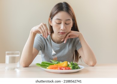 unhappy asian women is on dieting time looking at broccoli on the fork. girl do not want to eat vegetables and dislike taste - Shutterstock ID 2188562741
