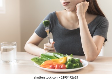 Unhappy Asian Women Is On Dieting Time Looking At Broccoli On The Fork. Girl Do Not Want To Eat Vegetables And Dislike Taste