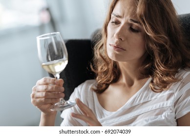 Unhappy beautiful woman looking at the glass of wine