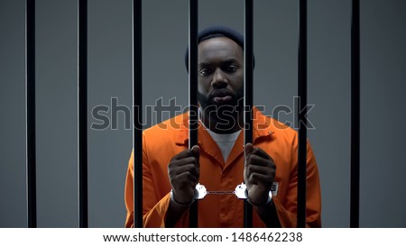 Unhappy black prisoner showing handcuffs, innocent male waiting for justice