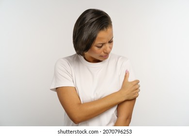 Unhappy Black Woman Suffer From Pain In Arm Touching Injured Shoulder With Painful Face Expression. Young African American Female With Hand Bone Fracture Or Dislocation. Injury Or Arthritis Disease