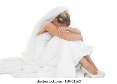 Unhappy blonde bride sitting on floor hiding her face