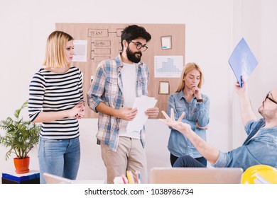 Unhappy boss having a conversation with afraid employees in the row while holding folder with bad results. - Shutterstock ID 1038986734