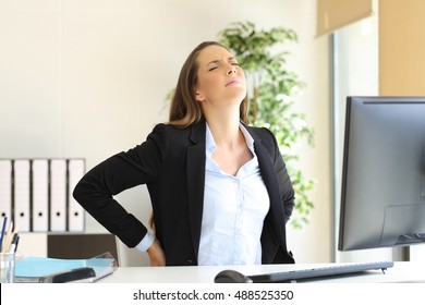 Unhappy Businesswoman Suffering Back Ache Sitting On An Uncomfortable Seat At Work Indoors In Her Office