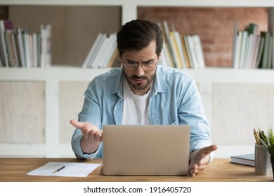 Unhappy Caucasian male employee work online on laptop in office frustrated by error or mistake on gadget. Upset mad man worker look at computer screen confused by slow internet or device breakdown.