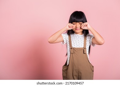 Unhappy Children. Asian Little Kid 10 Years Old Bad Mood Her Cry Wipe Tears With Fingers At Studio Shot Isolated On Pink Background, Child Girl Stress Feeling Sad Unhappy Crying