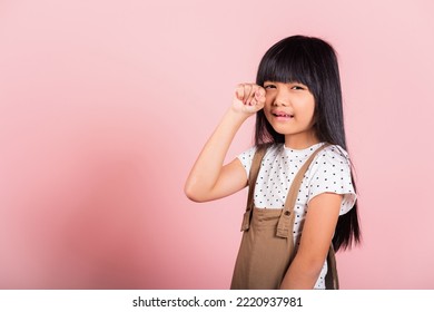 Unhappy Children. Asian Little Kid 10 Years Old Bad Mood Her Cry Wipe Tears With Fingers At Studio Shot Isolated On Pink Background, Child Girl Stress Feeling Sad Unhappy Crying