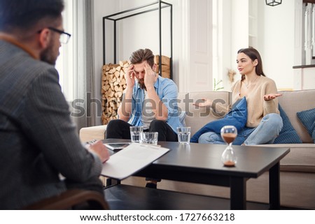 Unhappy couple arguing, having fight, disagreement at psychologists office, frustrated young family discussing relationship problems with their therapist