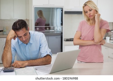 Unhappy Couple With Bills And Laptop In The Kitchen At Home