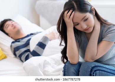 Unhappy couple, Depressed woman sits in bed while her boyfriend sleeps.