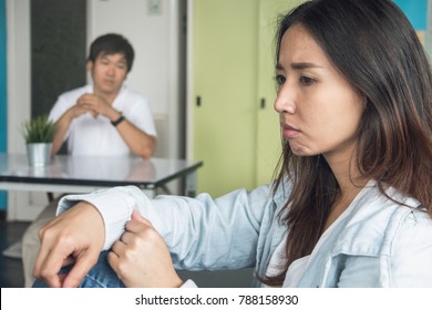 Unhappy Couple Not Talking After An Argument At Home. Depressed Woman Sitting On The Sofa And Sad Man Sitting On The Table Looking At Girlfriend. Selective Focus On Woman Face.