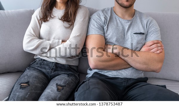 Unhappy couple not talking\
after an argument in the living room at home . Love, family and\
happiness concept - unhappy couple not speaking after having\
argument at home
