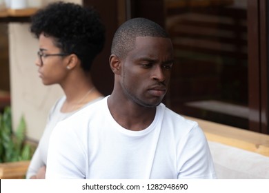 Unhappy Couple Sitting On Couch, Focus On Serious Sad American Man Thinking About Difficulties In Relationship, Spouses Not Looking At Each Other And Not Talking, Being In Quarrel. Break Up Concept