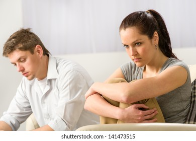 Unhappy Couple Sitting On Couch Silently After Argument