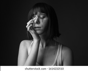 Unhappy crying young woman in studio. Black and white