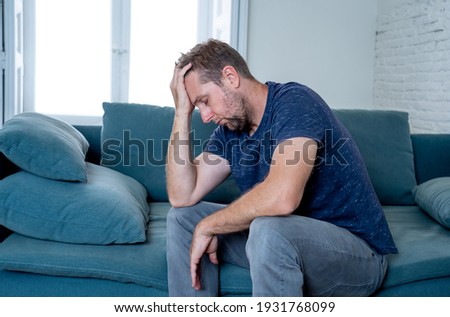 Unhappy depressed caucasian male crying in living room couch feeling desperate and lonely isolated at home. In stressed from work, unemployment, anxiety, heartbroken and depression concept