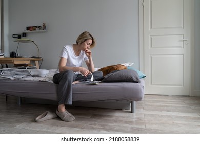 Unhappy Depressed Middle-aged Woman Living Alone With Dog Sits On Bed Counting Bills. Female Thinks On Paying Communal Debt. Mature Woman Has Difficult Life Without Money And Job After Husband Death