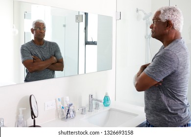 Unhappy Depressed Senior Man Looking At Reflection In Bathroom Mirror