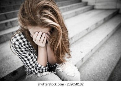 Unhappy Depressed Teenager With Face In Hands Sitting Outdoor