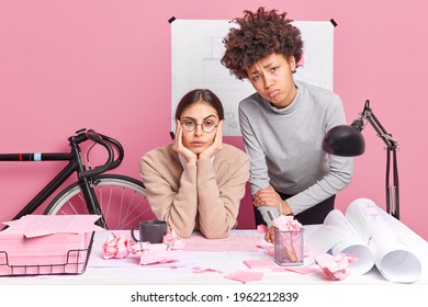 Unhappy diverse female classmates engeneering or training pose in coworking space make plannings for startup prepares architectural blueprints draw sketches prepare for brainstrorming session - Powered by Shutterstock