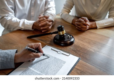 Unhappy divorce couple having conflict, husband and wife during divorce process with senior male lawyer or counselor and couple signing decree of divorce contract in lawyer's office.
