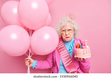 Unhappy Elderly Woman Celebrates 91st Birthday Upset About Her Old Age Wears Small Crown On Head Festive Clothes With Jewelry Holds Cake And Bunch Of Helium Balloons Waits For Party To Start