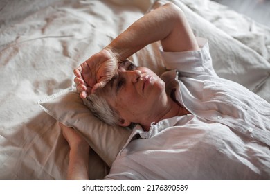 Unhappy elderly woman lying in bed at home thinking pondering over life problems, mourning or yearning, upset sad senior female relax in bedroom feel unwell or stressed suffering from insomnia