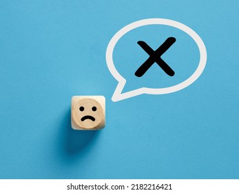 Unhappy Face Icon On A Wooden Cube With Cross X Or No Sign In A Speech Bubble. No Or Rejection Concept.