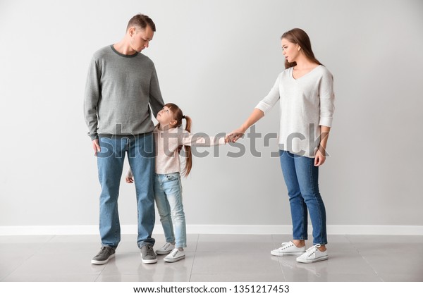 Unhappy family\
after divorce against light\
wall