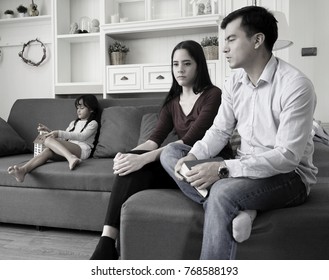 Unhappy Family Concept. The  Sad Face Of  Parent Sitting On The Sofa With Daughter In Background. Angry Boyfriend And Sad Girlfriend At Home. Couple Worried After Argument. Black And White Picture.