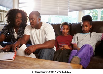 Unhappy Family Sitting On Sofa Looking At Bills