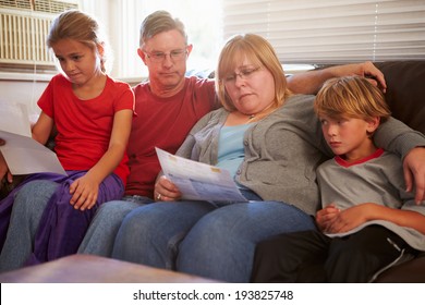 Unhappy Family Sitting On Sofa Looking At Bills