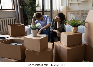 Unhappy frustrated couple sitting on couch with cardboard boxes, eviction, family having problem with dwelling, money or mortgage, worried woman and man lost home, bankruptcy or debt concept