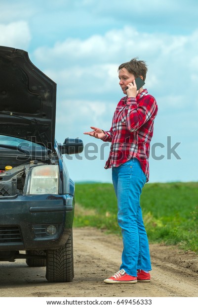 Unhappy frustrated female\
calling car mechanic repair shop with mobile phone from country\
dirt road