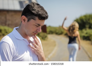 Unhappy Frustrated Man In Focus And Angry Woman Leaving On The Background After Quarrel