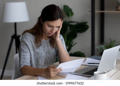 Unhappy frustrated woman reading bad negative news in letter, sitting at desk, upset young businesswoman shocked by unexpected loan debt, bank or job dismissal notification, eviction notice