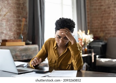 Unhappy frustrated young African American woman feeling stressed managing financial affairs or mistakes, suffering from lack of money calculating business expenditures, accounting, bankruptcy concept.