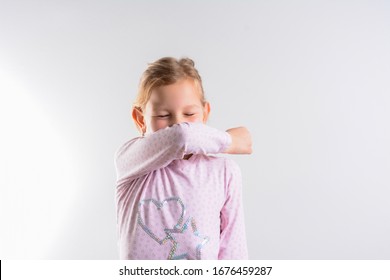 Unhappy Girl Cough Into Her Elbow, Not Her Hand. Child Pull The Collar Of Her T-shirt Up To Cover Mouth When Coughing. Coughing Advice From Experts Who Seek To Minimize Risk Of Viral Transmission