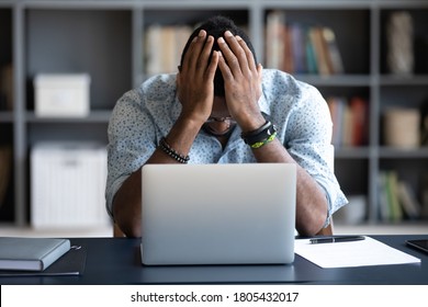 Unhappy hopeless African American man holding head in hands, overwhelmed tired businessman sitting at work desk with laptop, feeling exhausted, financial problem, loss money or bankruptcy - Shutterstock ID 1805432017
