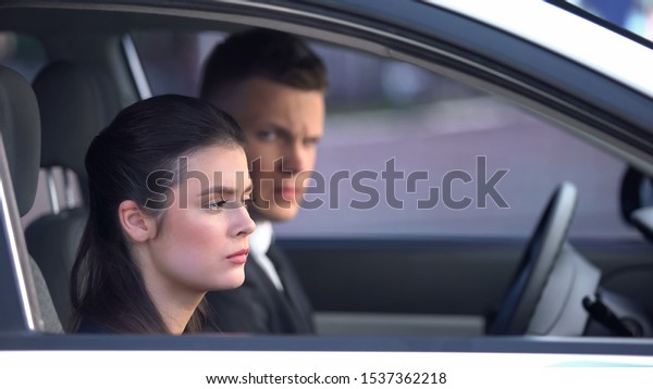 Unhappy husband and wife sitting in car after\
fight, risk of divorce,\
quarrel