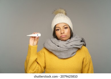 Unhappy Ill Female In Warm Scarf Showing Thermometer And Suffering From Fever. Upset African American Woman On Sick Leave Feel Bad And Unhealthy. Seasonal Flu Illness Or Coronavirus Treatment Concept